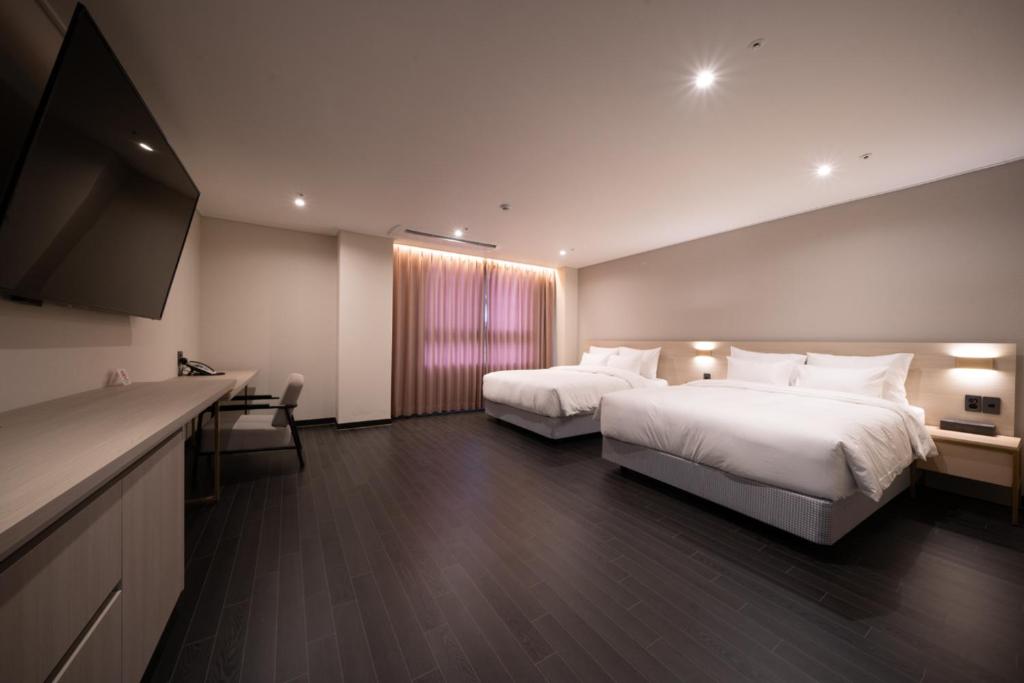 ein Hotelzimmer mit 2 Betten und einem Flachbild-TV in der Unterkunft Hotel SUMMIT in Gwangju