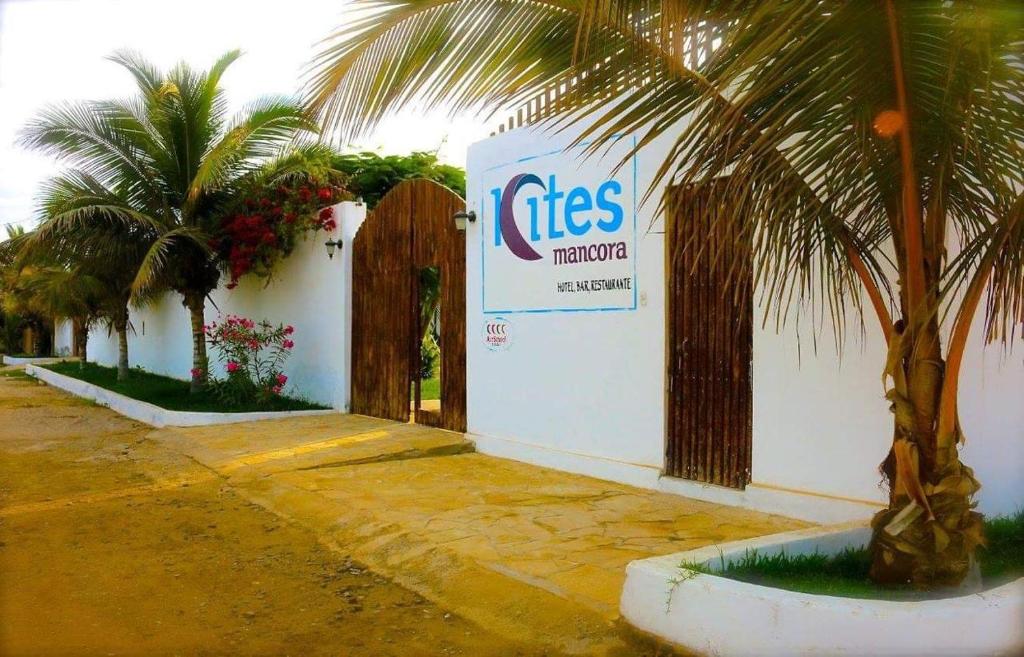 ein Gebäude mit einem Schild neben Palmen in der Unterkunft Kites Mancora in Máncora