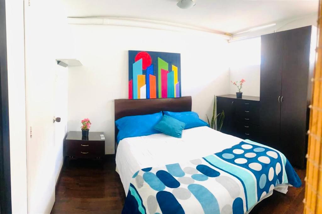 a bedroom with a bed with blue and white sheets at Hostel Usaquen Bogota in Bogotá