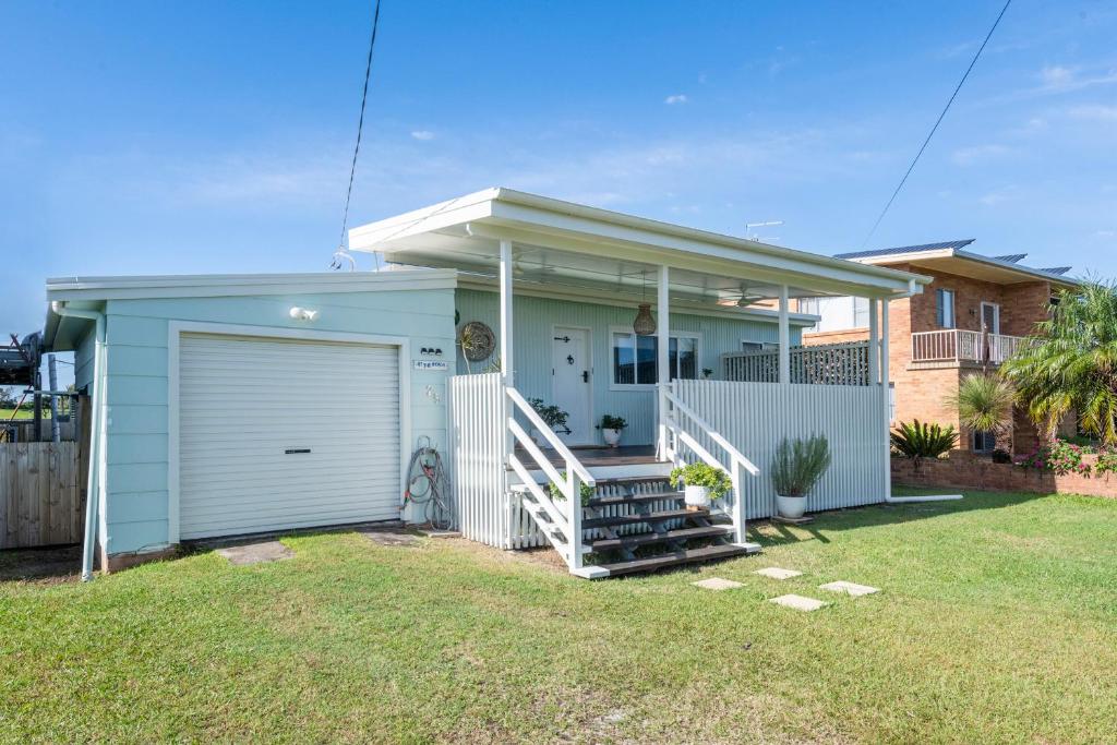 una casa azul con un garaje en un patio en At The Beach Brooms Head-LJHooker Yamba en Brooms Head