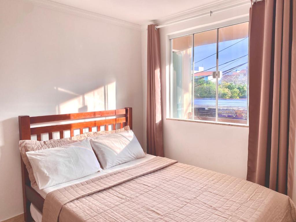 um quarto com uma cama e uma janela grande em Apartamento Apês do Peró 10 - centro - 5 pessoas em Cabo Frio