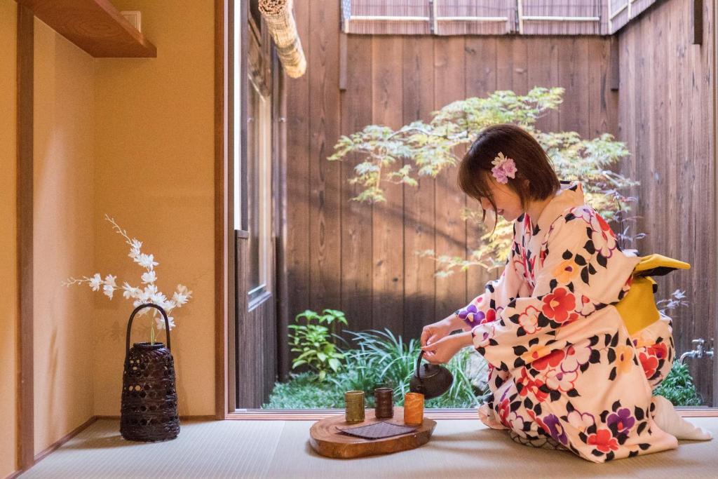 a woman in a kimono sitting next to a window playing with candles at 京町　朱雀 in Kyoto