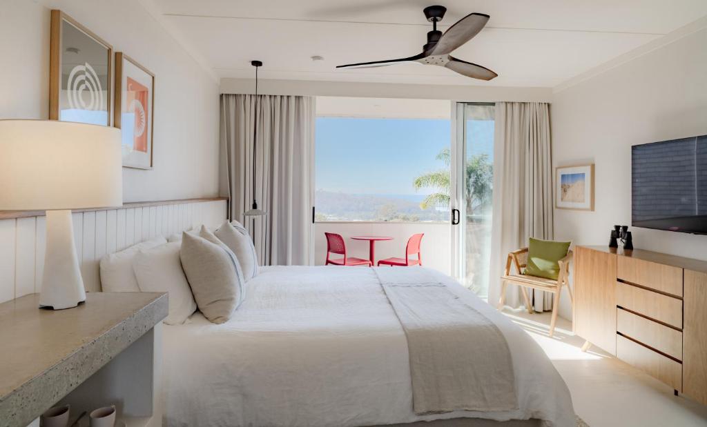 a bedroom with a white bed and a large window at Hillcrest Merimbula in Merimbula