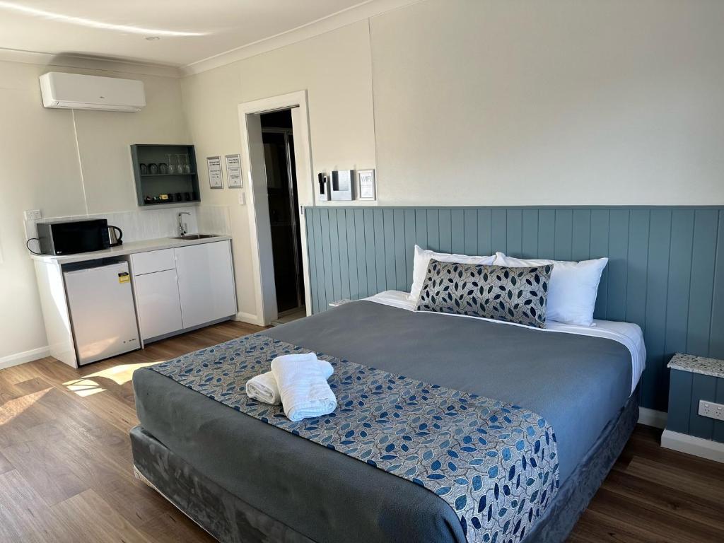 a bedroom with a large bed and a kitchen at Surf Beach Motel Newcastle in Newcastle