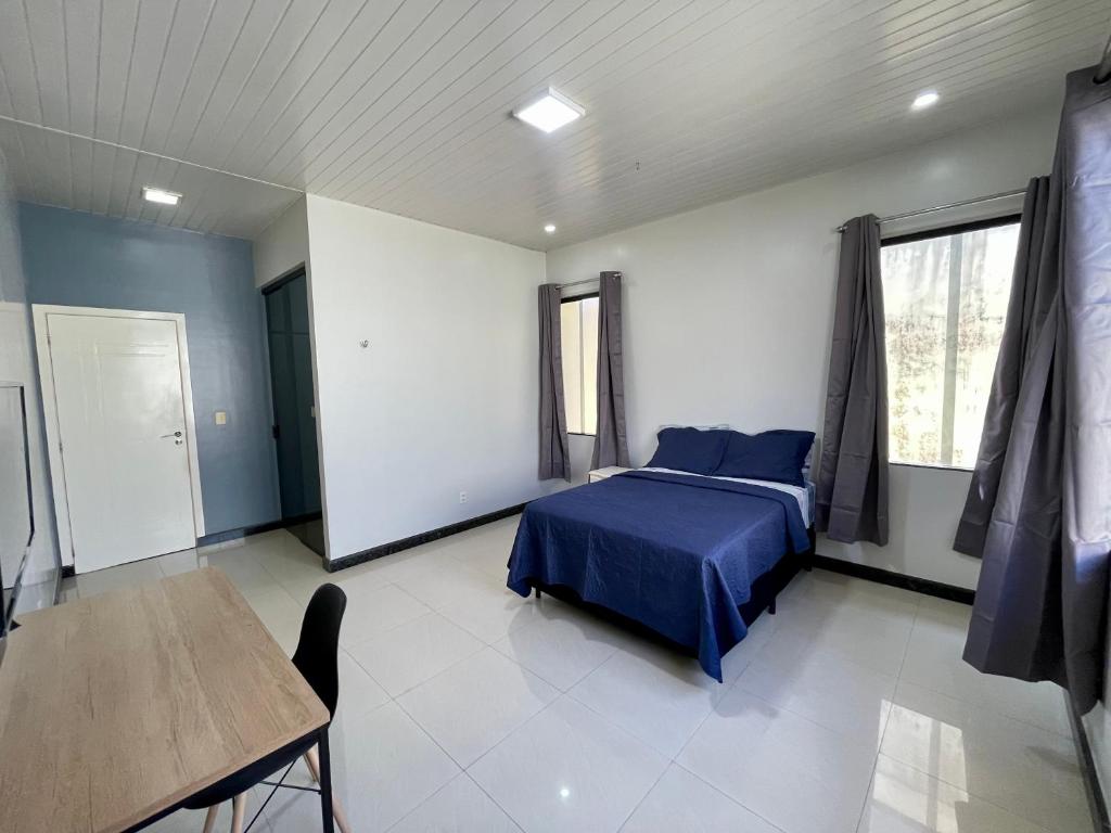 Un dormitorio con una cama azul y una mesa en Casa completa, suíte master com closet, en Macapá