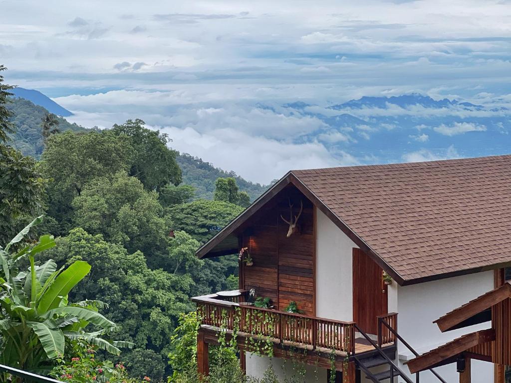 a house with a balcony and mountains in the background at Baan Nhuer Mek บ้านเหนือเมฆ Coffee and Desk on the Cloud 