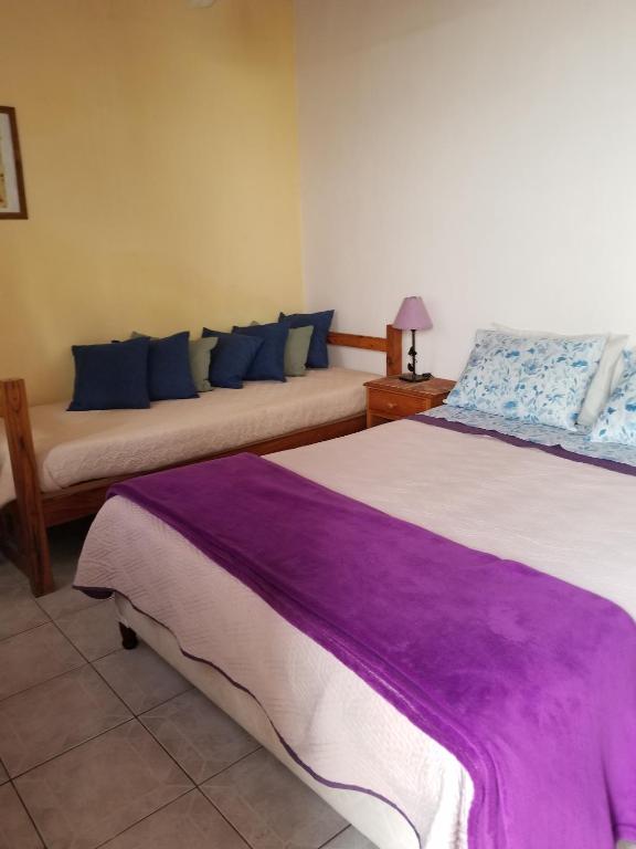two beds in a room with purple sheets at La Casa de Teresa in Colonia del Sacramento
