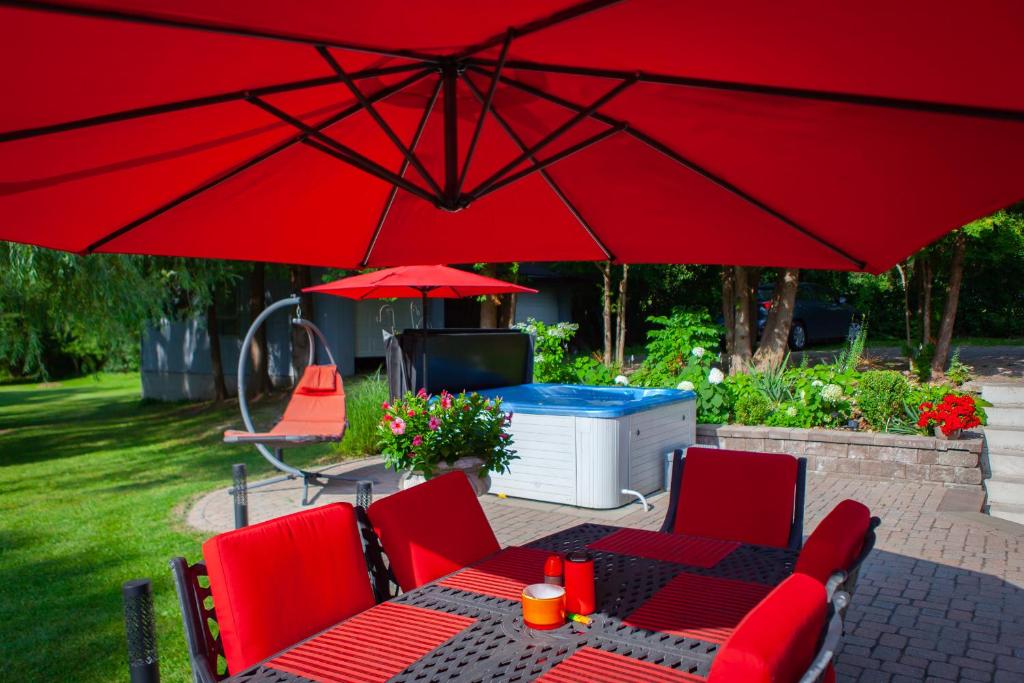 une table et des chaises sous un grand parapluie rouge dans l'établissement Nature Oasis Bar Room, à Dundas