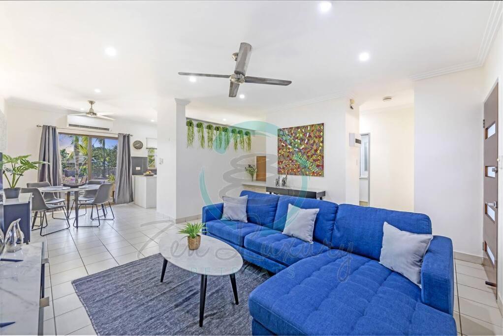 a living room with a blue couch and a table at Zen by the Coast: 2-BR Cozy Retreat Near Uni/Shops in Casuarina