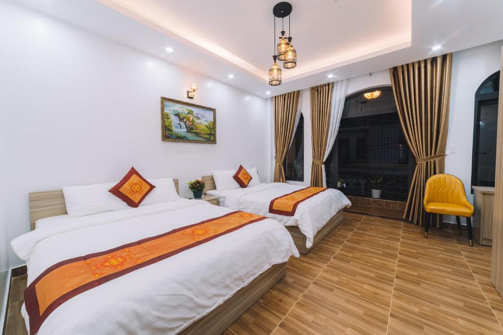 um quarto de hotel com duas camas e uma cadeira amarela em Út Thảo 2 em Da Lat