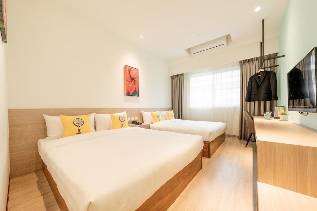 a hotel room with two beds and a desk at TH Hotel in Pingtung City