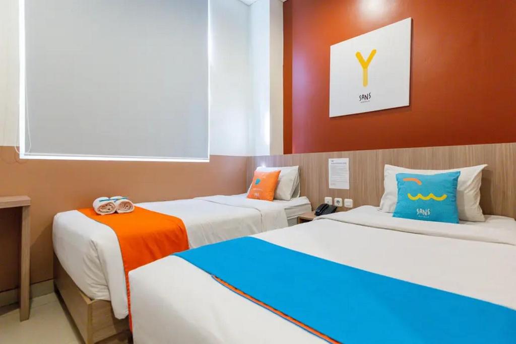 a room with two beds with orange and blue at Sans Hotel Rajawali Surabaya by RedDoorz in Krembangan