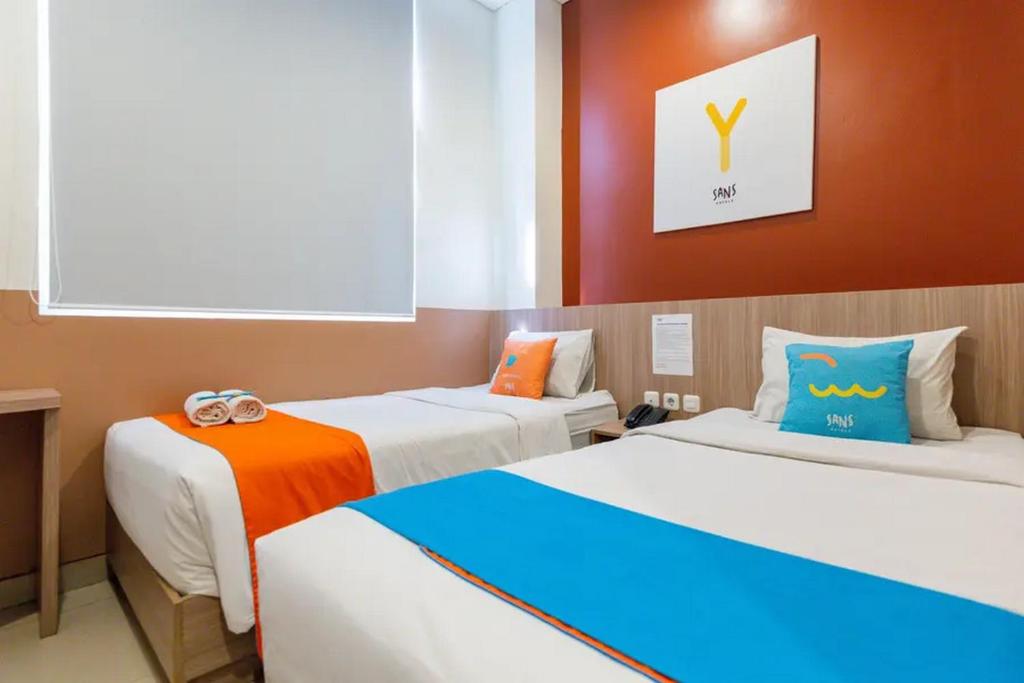 een kamer met twee bedden met oranje en blauw bij Sans Hotel Rajawali Surabaya by RedDoorz in Krembangan