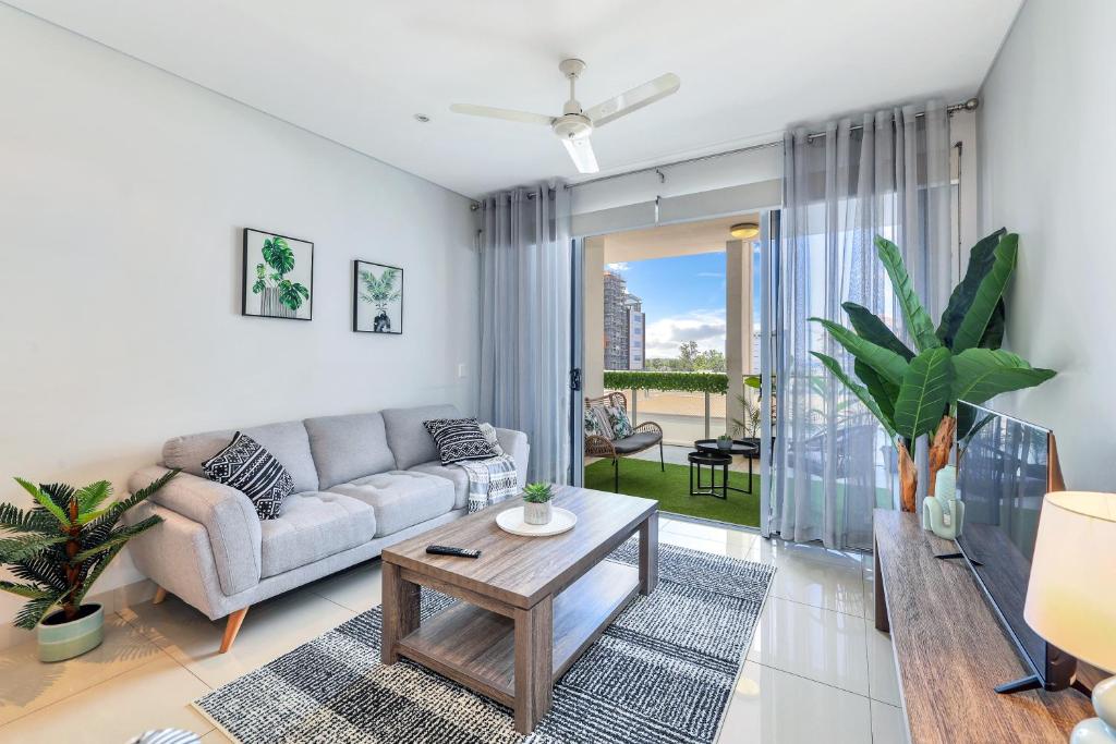 a living room with a couch and a table at Central City Apartment, Pool & Gym, 2 car parks in Darwin