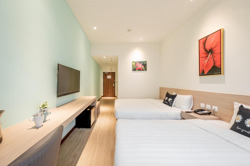 a hotel room with two beds and a flat screen tv at TH Hotel in Pingtung City