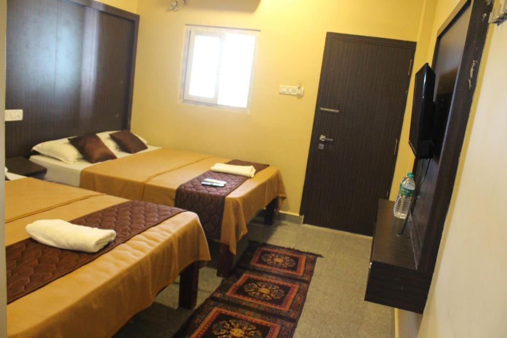 Habitación de hotel con 2 camas y TV en gSR RESIDENCY en Kanchipuram