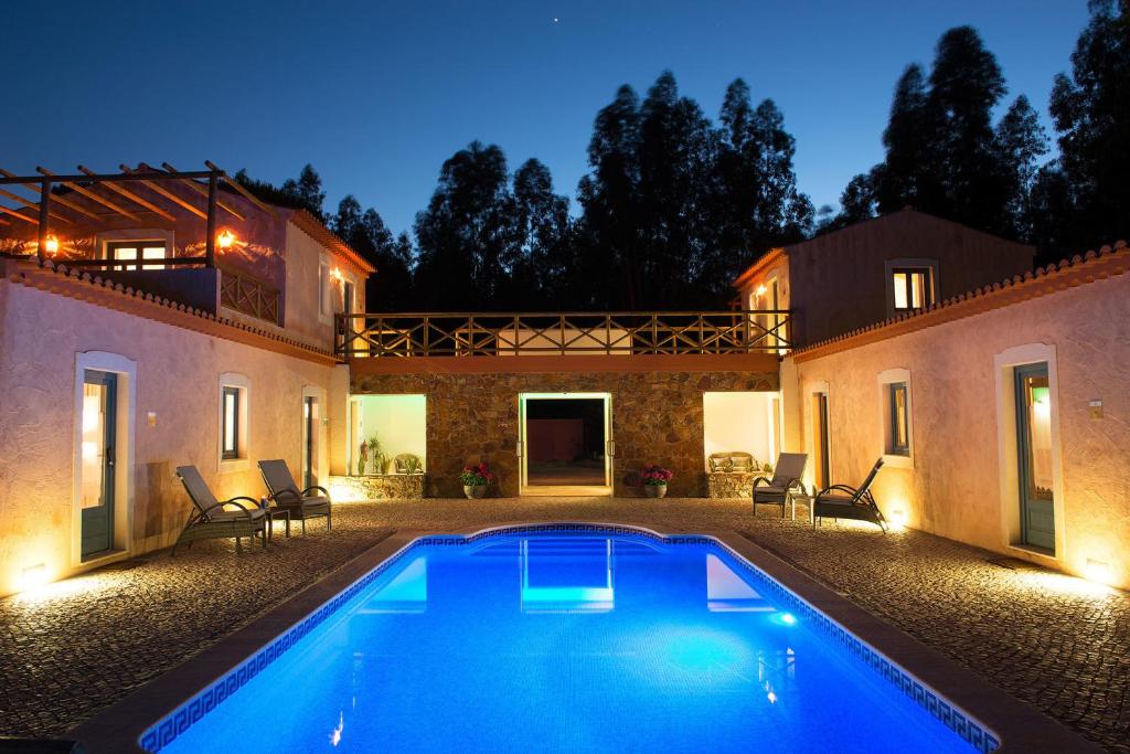 una piscina en el patio trasero de una casa por la noche en Monte Soalheiro en Zambujeira do Mar