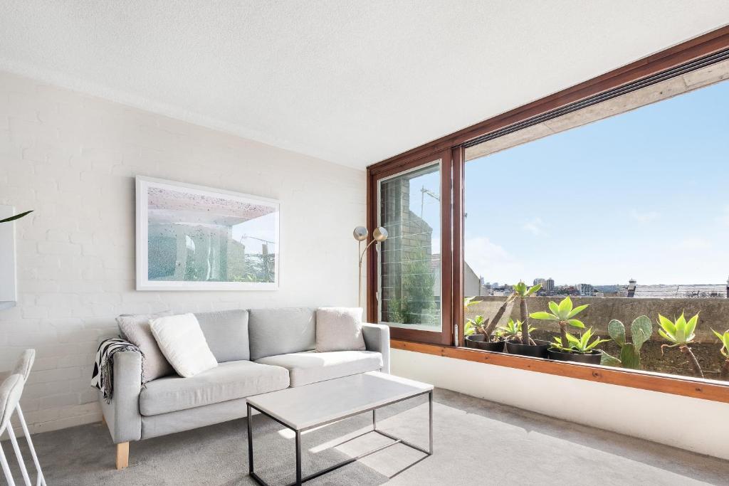 ein Wohnzimmer mit einem Sofa und einem großen Fenster in der Unterkunft Boutique Paddington Apartment with CBD Views in Sydney