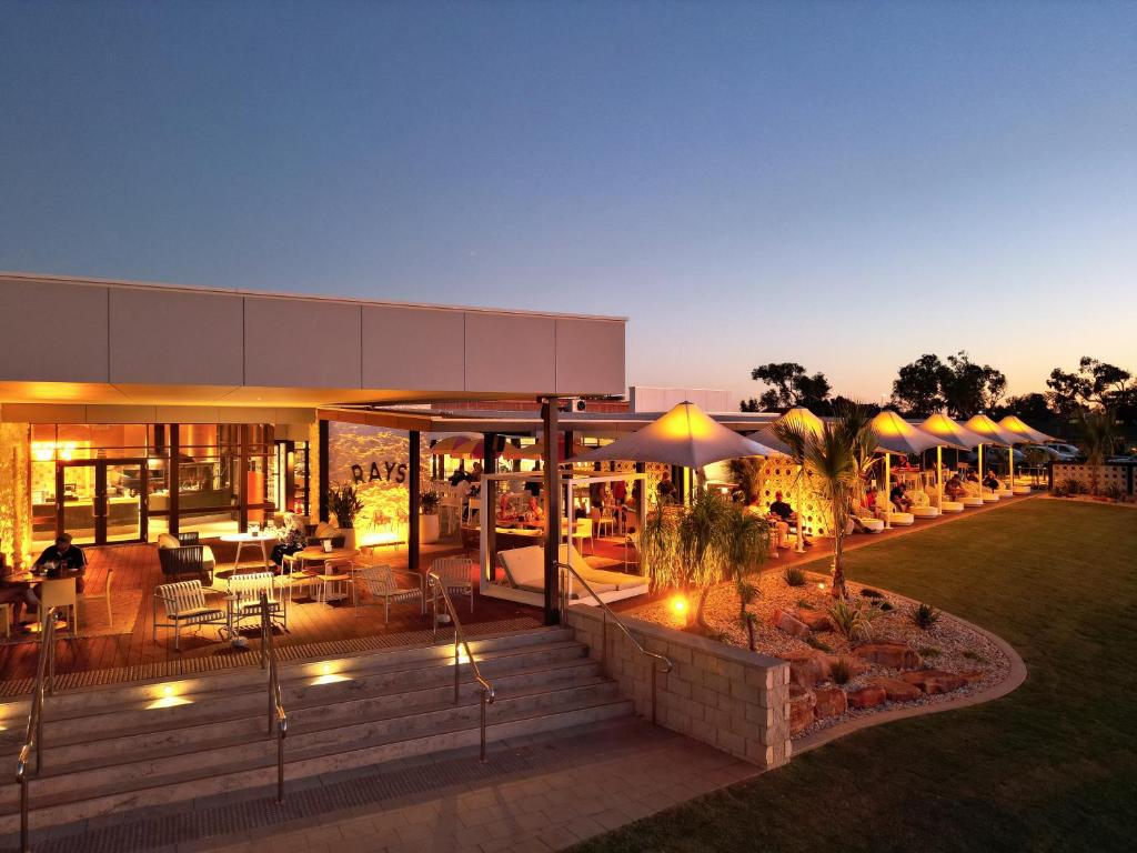 a building with tables and umbrellas in a yard at Hedland Hotel in Port Hedland