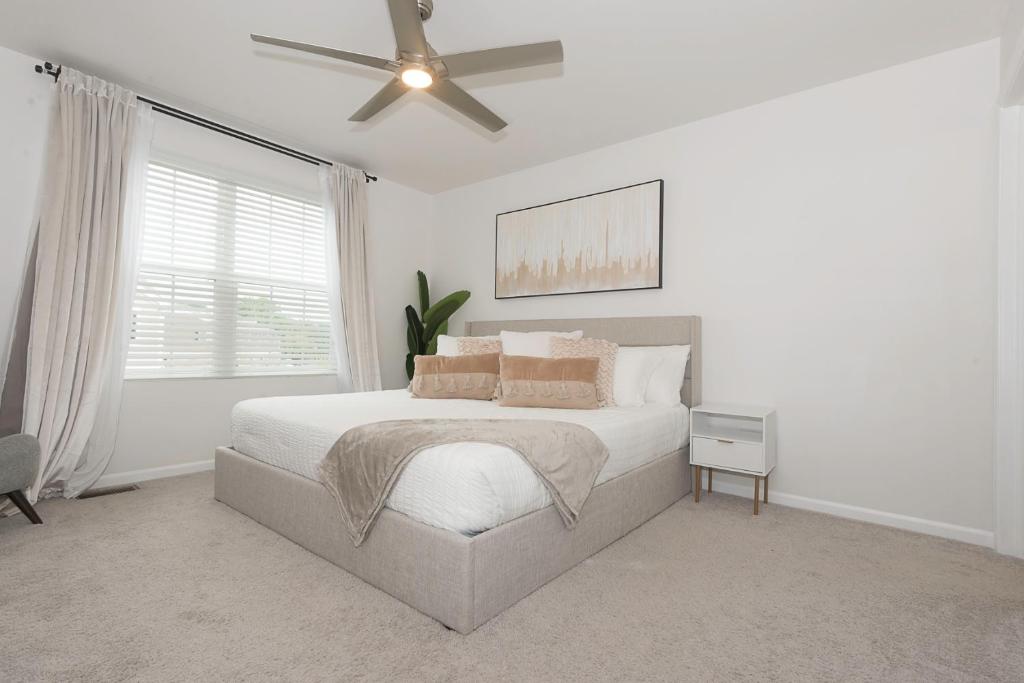 een witte slaapkamer met een bed en een plafondventilator bij Urban Oasis in Chicago’s Best Suburb in Naperville
