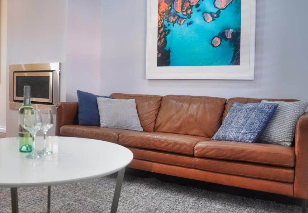 a living room with a brown couch and a white table at Balneaire 13 in Albany