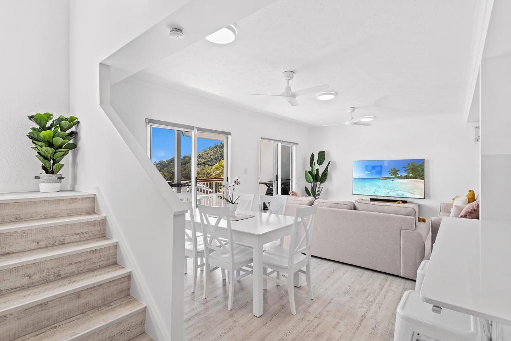 a white living room and dining room with a white table at The View in Cannonvale