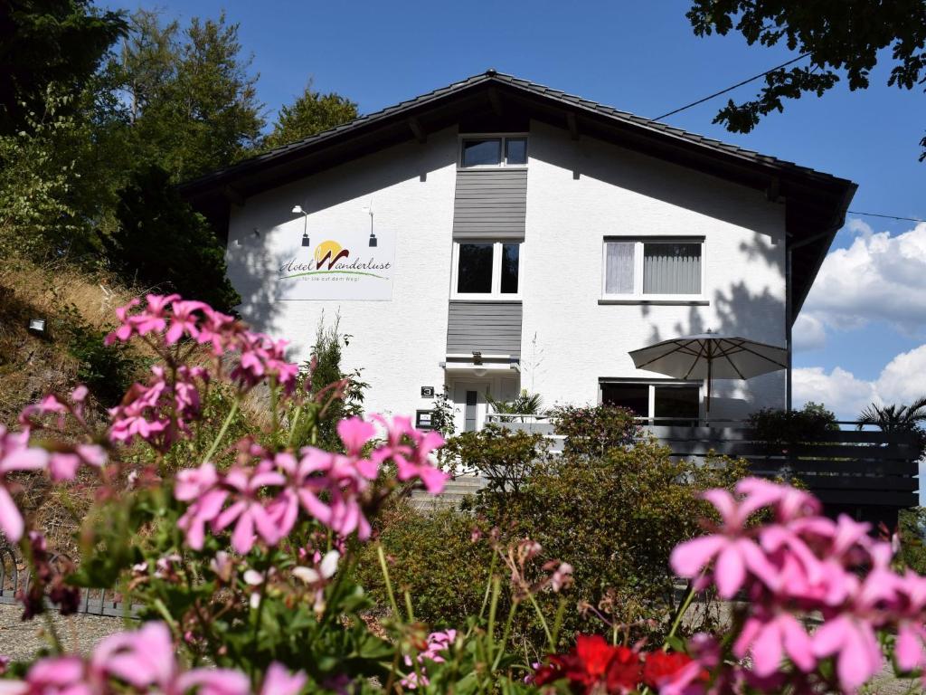 ein weißes Gebäude mit rosa Blumen davor in der Unterkunft Hotel Wanderlust B&B in Gernsbach