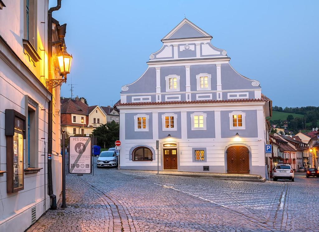 a large white building with a turret on a street at Penzion KOVÁRNA in Český Krumlov