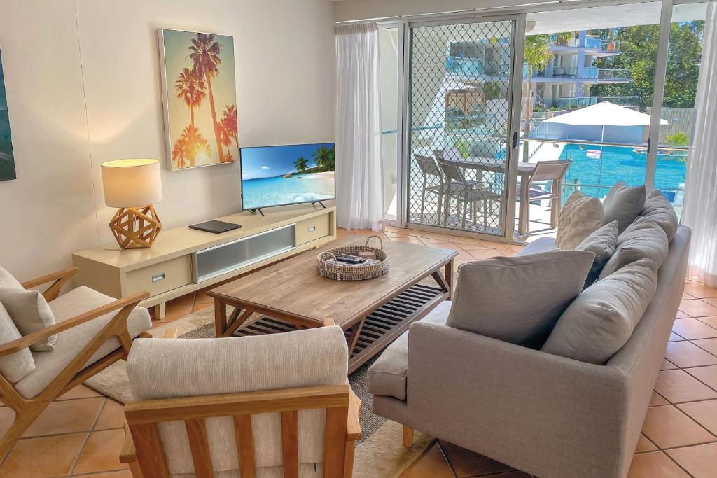 uma sala de estar com um sofá, uma televisão e uma mesa em The Cove Noosa - Apartment 6 em Noosa Heads