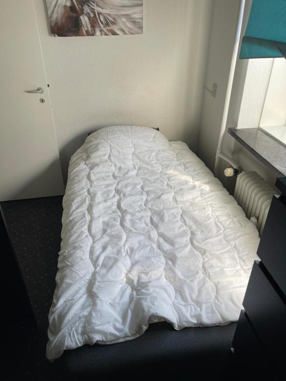 an unmade bed in a room with a white comforter at Nice room near airport in Copenhagen
