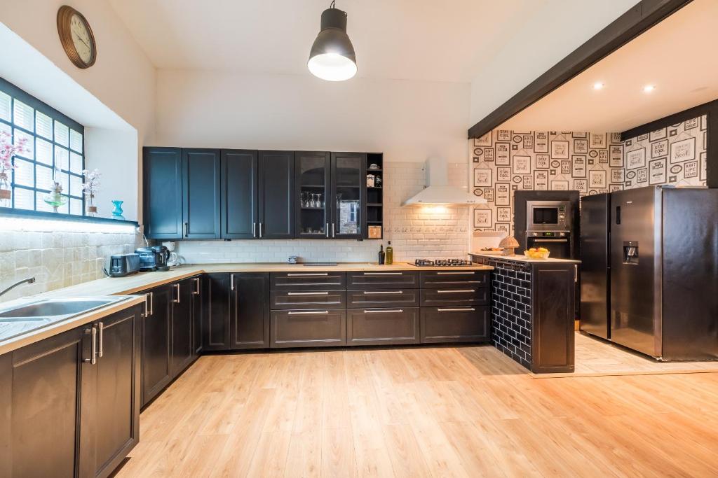 a large kitchen with black cabinets and wooden floors at Les Choucas - Maison pour 9 avec terrasse in Plouaret