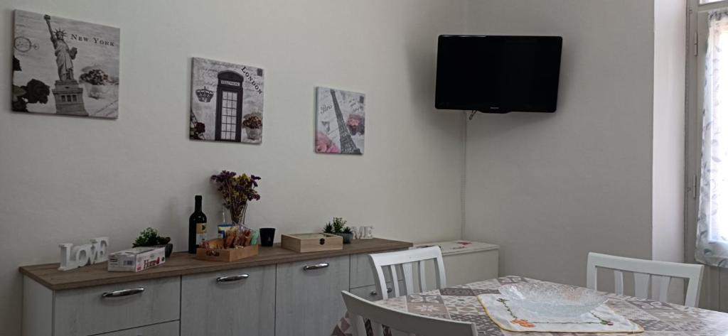 ein Esszimmer mit einem Tisch und einem TV an der Wand in der Unterkunft La casa di Ali in Abbadia San Salvatore