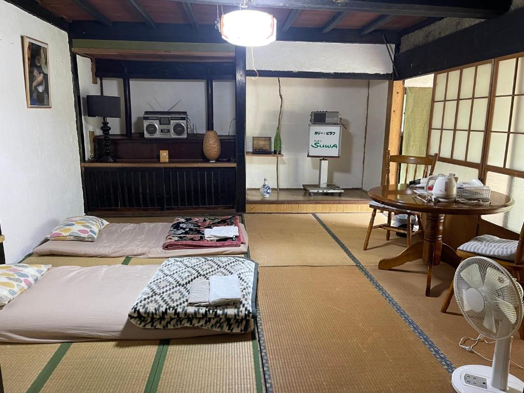 Habitación con 2 camas y mesa con ventilador. en 楽園晩御飯(rakuyenbangohan), en Yame