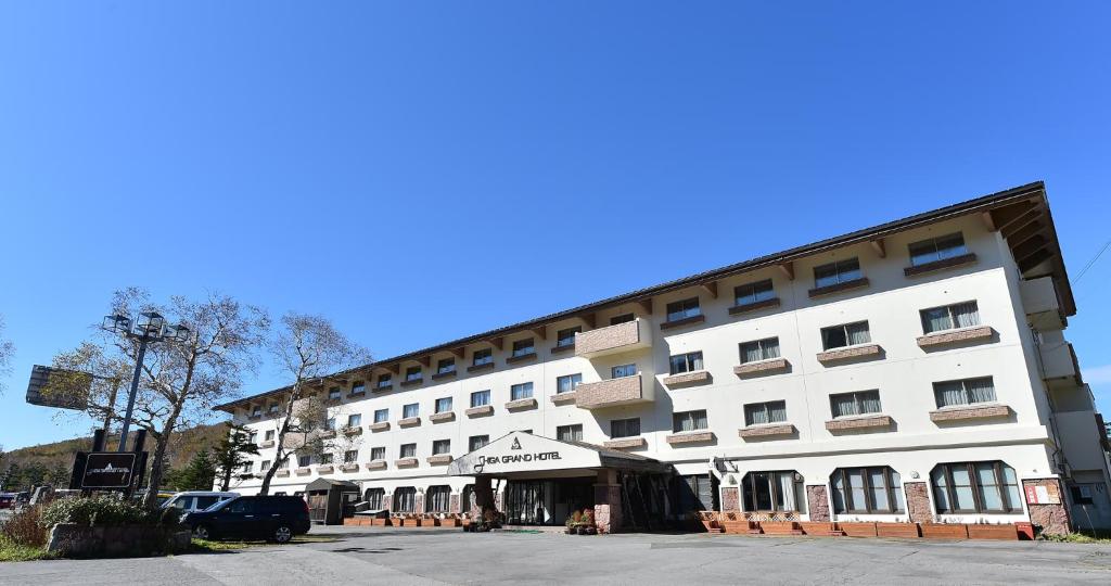 a large white building with a parking lot in front of it at Shiga Grand Hotel in Yamanouchi