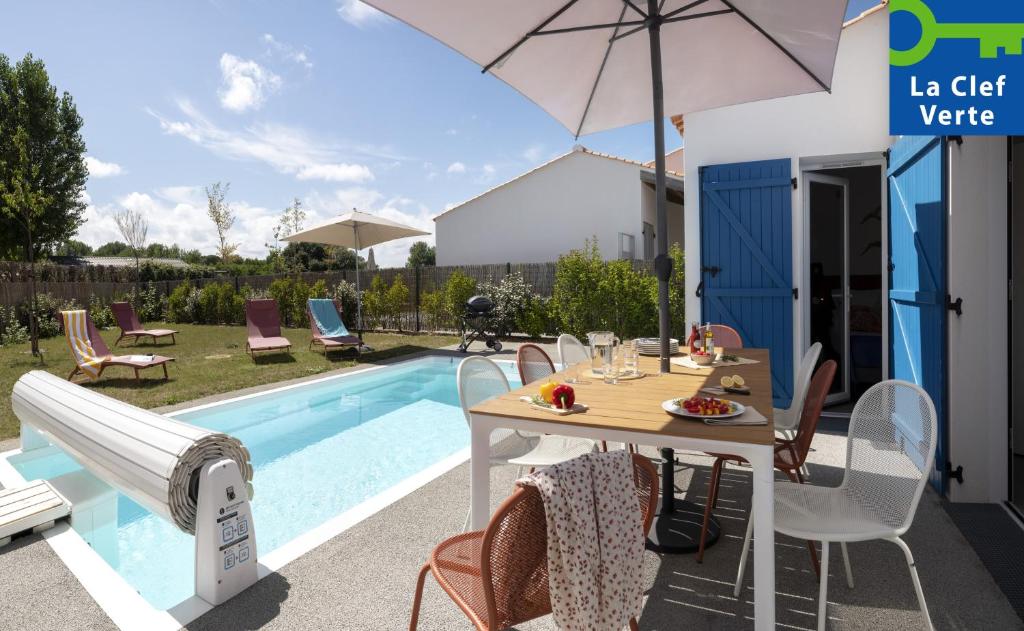 um pátio com uma mesa e um guarda-sol ao lado de uma piscina em Pierre & Vacances Premium Les Villas d'Olonne em Les Sables-dʼOlonne