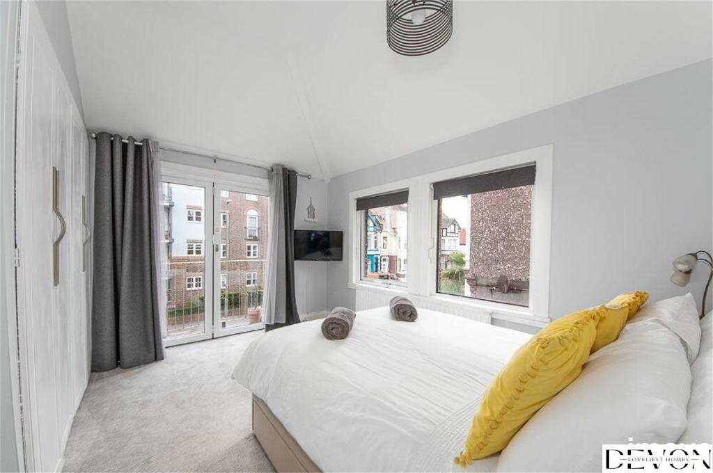 - une chambre blanche dotée d'un lit avec une couverture jaune dans l'établissement Loveliest Homes Paignton - Casa Marina - 3 bed, 2 bathroom house, balcony, parking, à Paignton