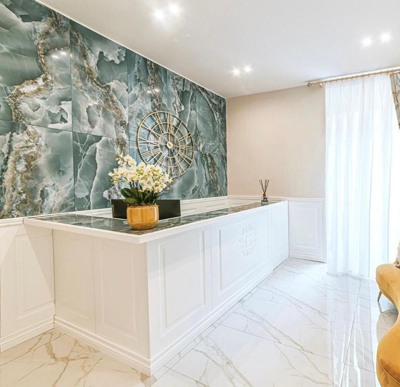 una cucina con bancone bianco e orologio sul muro di Gentile Suite & Spa Vomero a Napoli
