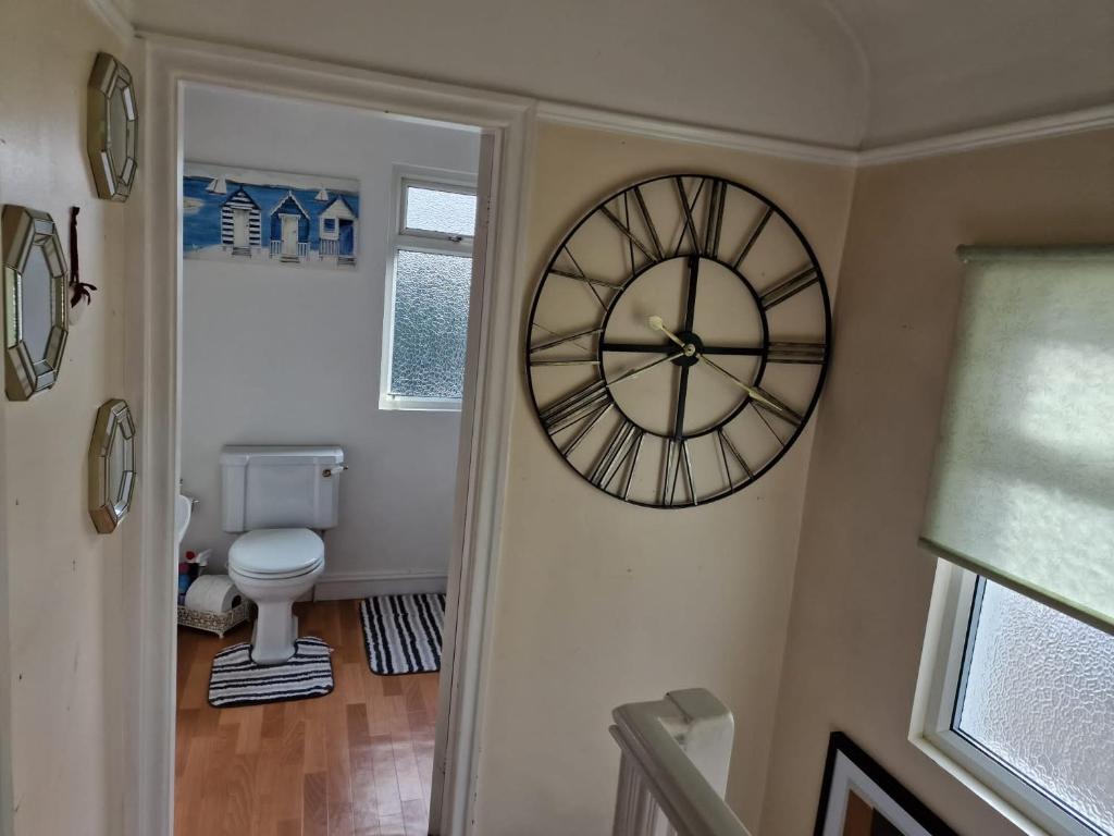 a clock on the wall of a bathroom with a toilet at Room in North Watford in Garston
