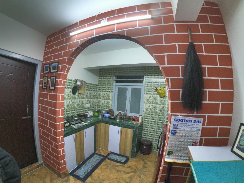 a kitchen with a red brick wall with a mirror at Blue Valley Apartment in Darjeeling