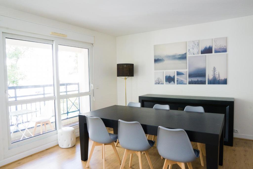 comedor con mesa negra y sillas en EXIGEHOME-Beautiful apartment, 2 bedrooms 70m2 15 min from Paris, en Rueil-Malmaison