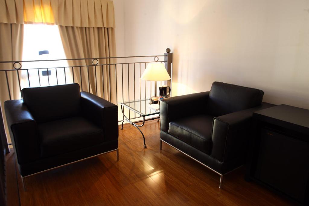 a living room with two black chairs and a lamp at Hotel San Rocco in Muggia