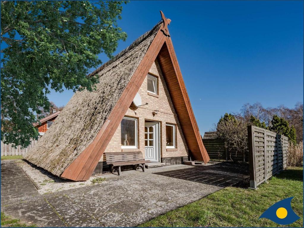 Casa pequeña con techo de paja y banco en Reetdachhütte im Birkenhain en Trassenheide
