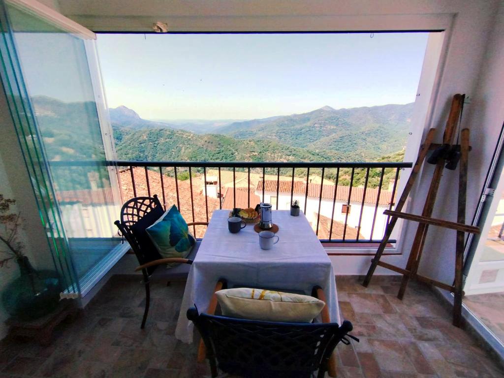 a table and chairs in a room with a large window at Casa Perejil, un balcón al Genal in Genalguacil