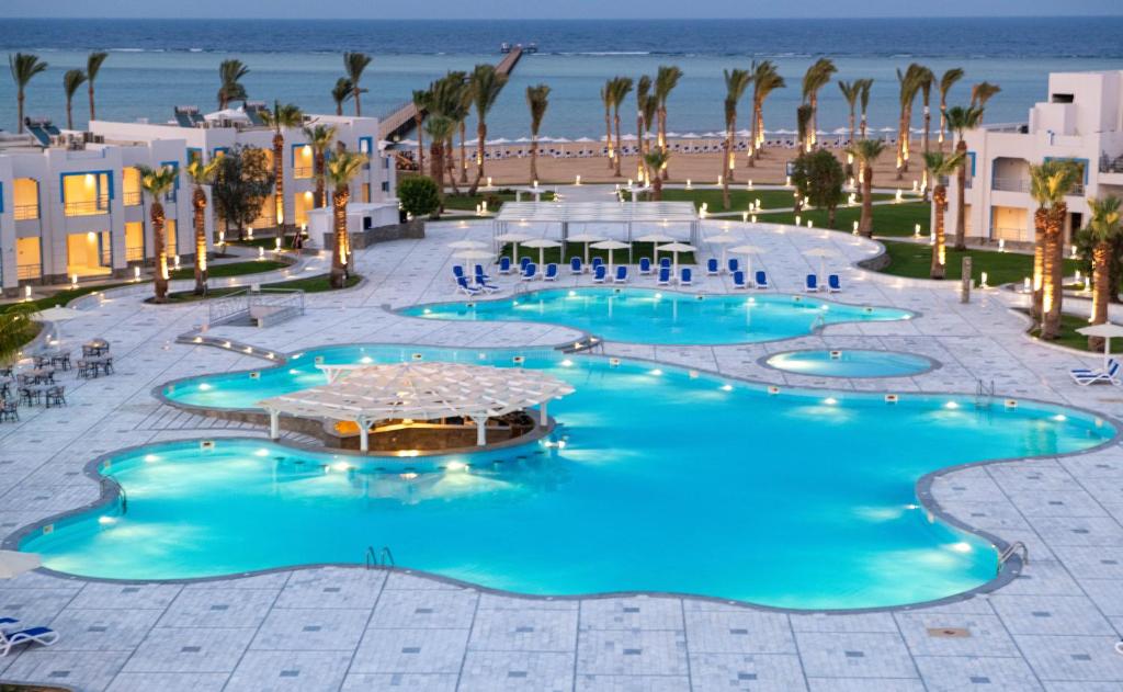 uma vista sobre uma piscina de resort com palmeiras e a praia em Casa Blue Resort em Marsa Alam