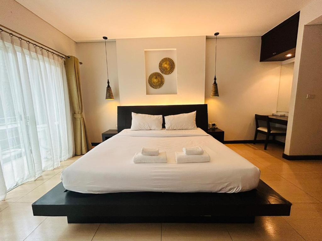 a bedroom with a large white bed with two towels at โรงแรม ดิ โอวาเล่ย์ [The O Valley Boutique Hotel] 