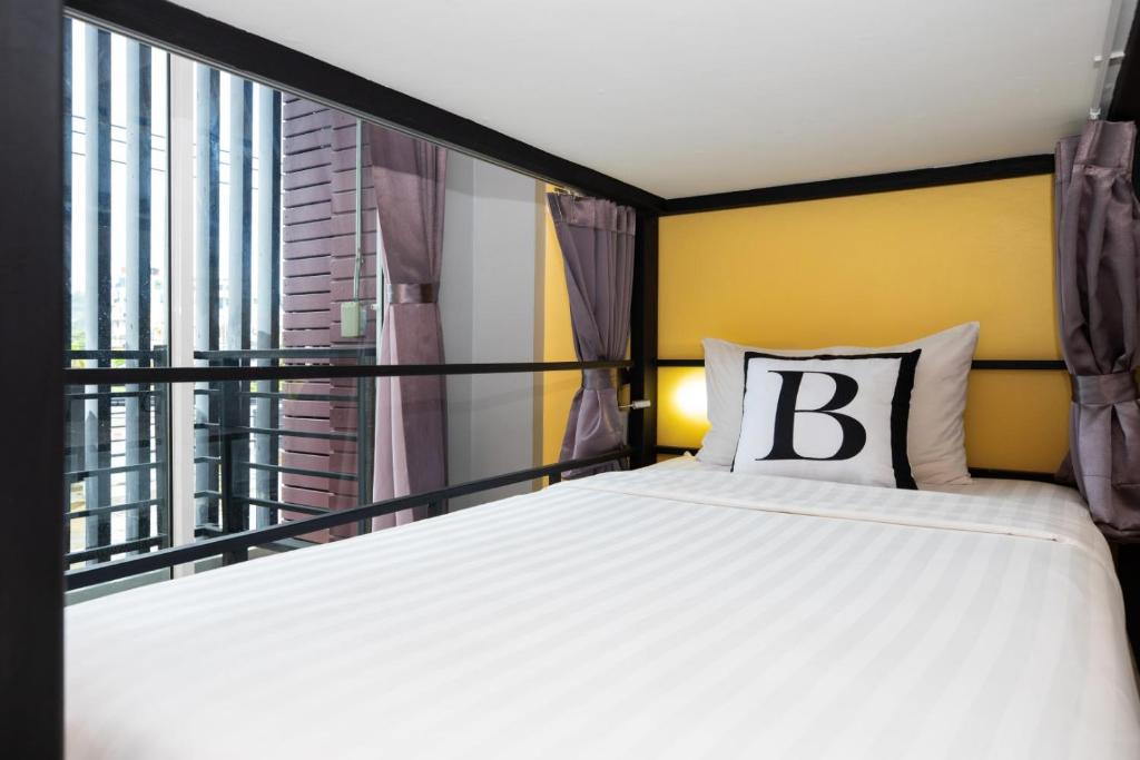 a bedroom with a bed and a large window at Bell Lifestyle Hostel Phuket in Nai Yang Beach