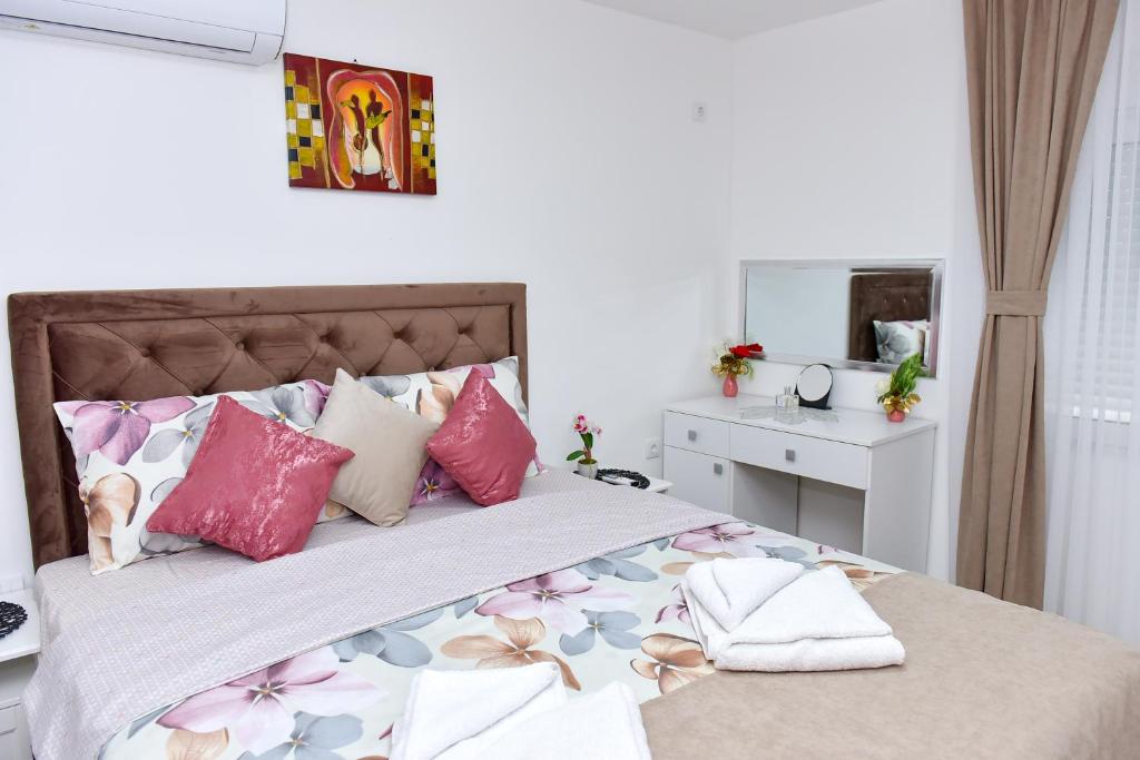 1 dormitorio con 1 cama con almohadas rosas y moradas en Apartmani Simić en Kuršumlija