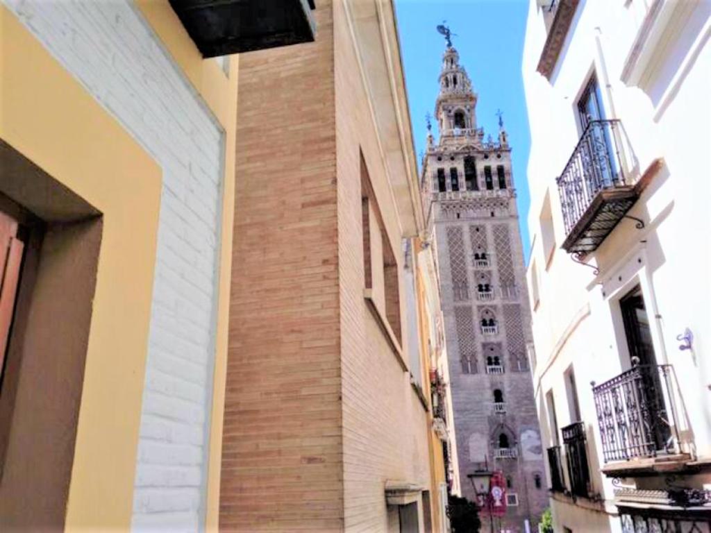 a tall building with a clock tower in the distance at ¡EN FRENTE DE LA GIRALDA-CATEDRAL! in Seville