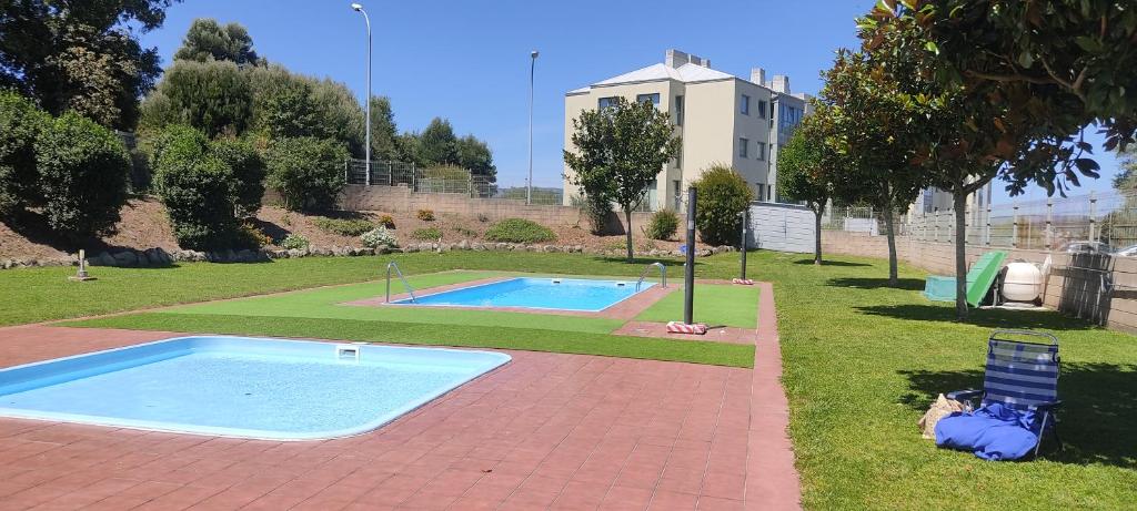 ein Schwimmbad in einem Park mit einem Gebäude im Hintergrund in der Unterkunft PISO EN GALICIA RIAS BAIXAS CON PISCINA Y GARAJE Urbanización privada en Rianxo in Rianjo