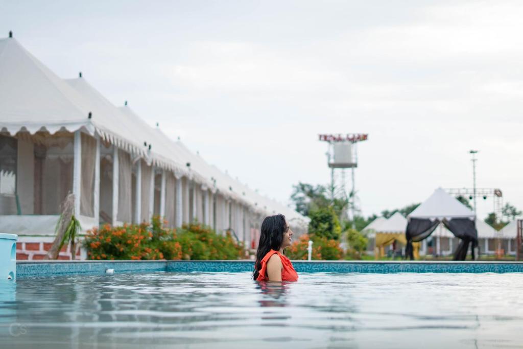 uma mulher está de pé numa piscina de água em The Royal Heritage Tent Resort- Statue of Unity em Navgam